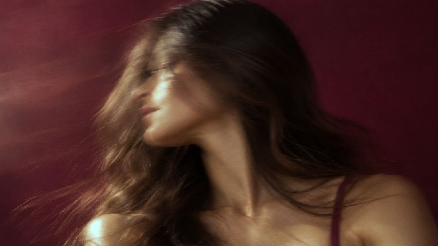 Motion-blurred portrait on a burgundy background